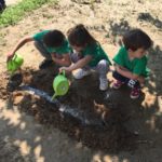 tre bambini con maglietta verde innaffiano