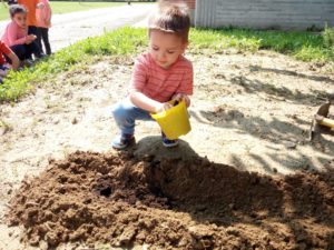 bambina che ricopre i semi con la terra