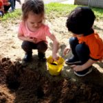 bambini che tirano la terra da un secchiello giallo