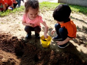 bambini che tirano la terra da un secchiello giallo